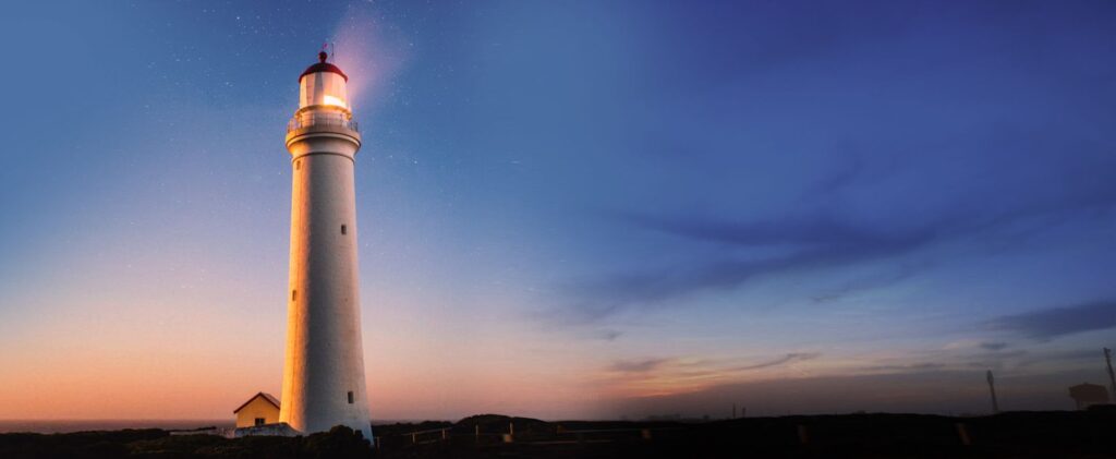 Illuminated lighthouse beacon at dusk representing the vision and direction of Associated Alcohols & Breweries